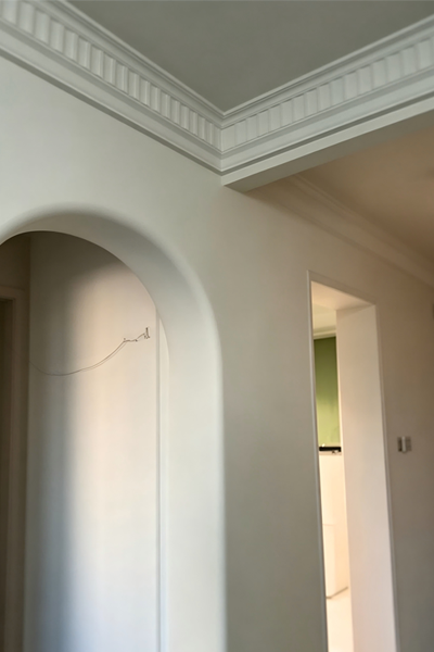 Curved plaster wall with linear light, fitted with corner bead moulding strips for smooth rounded edges.